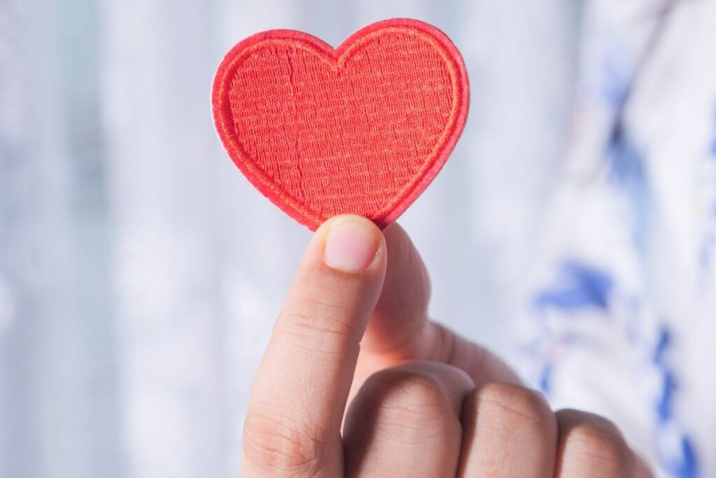 volunteer image with hand holding a fabric heart.