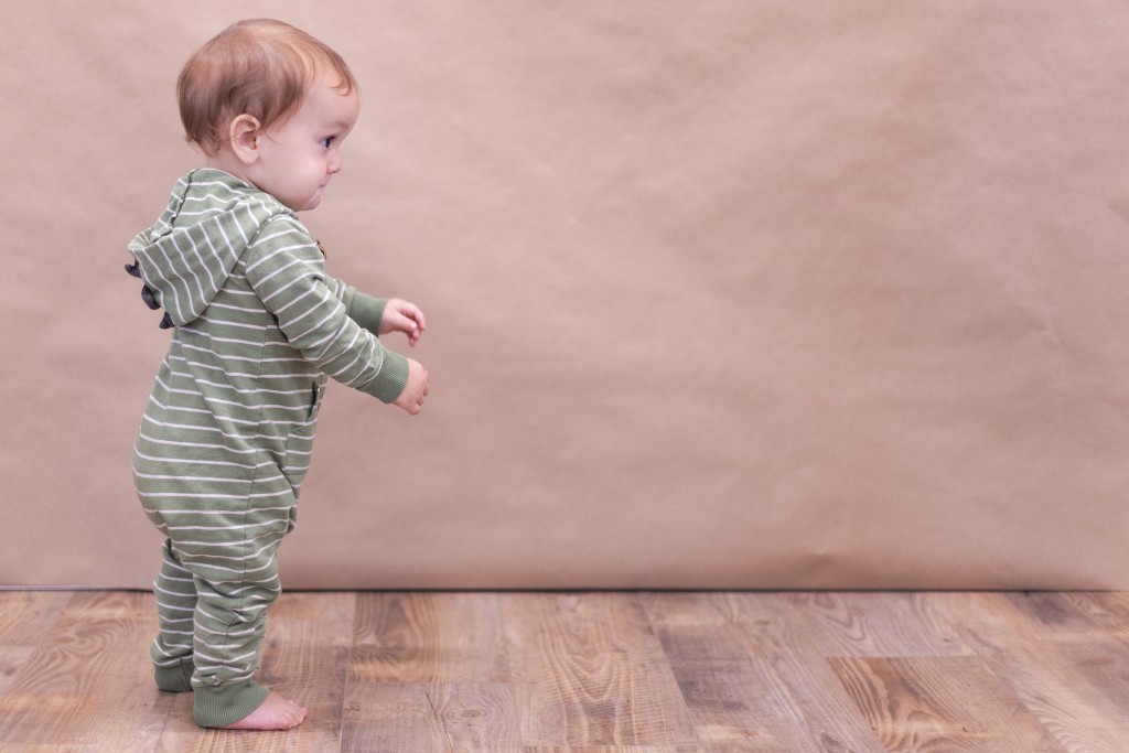 One year old baby walking across the floor