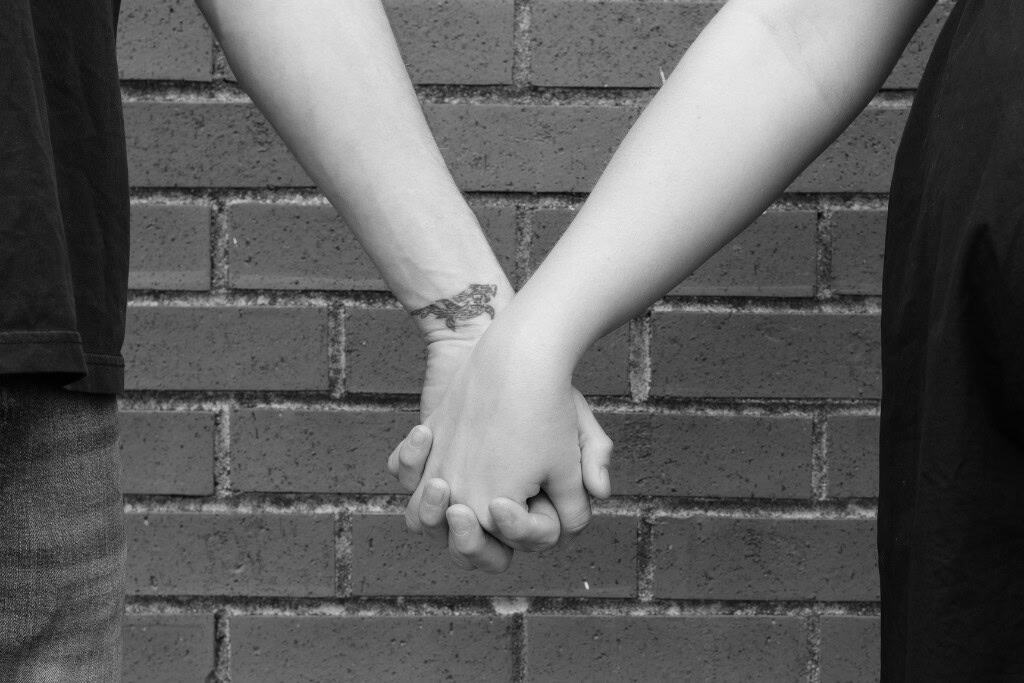 Mom and dad holding hands against brick wall